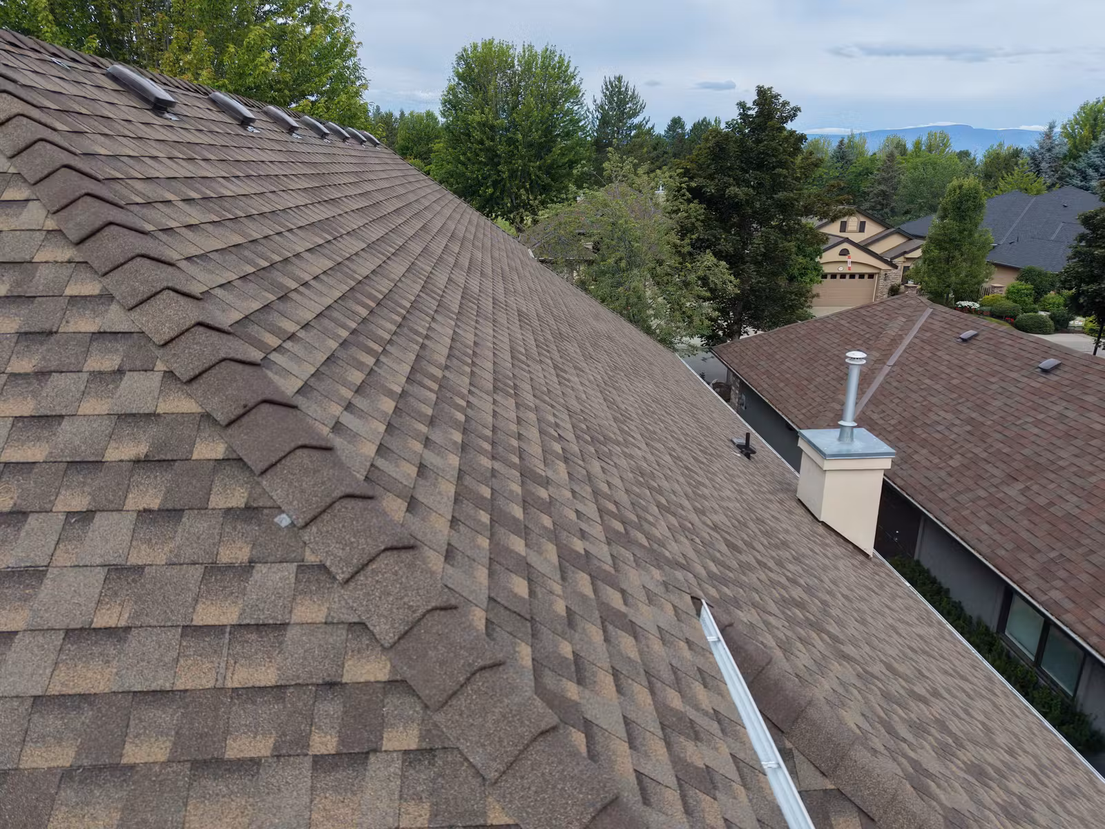 Close aerial view of completed shingles and chimney on an East Kelowna roof